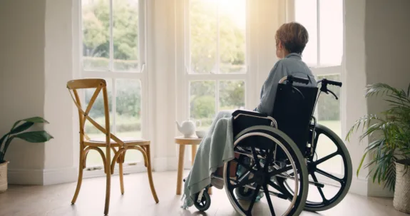 Older woman in wheel chair looks out a window